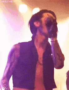 a man without a shirt is singing into a microphone ..