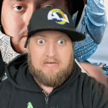 a man with a beard wearing a black hat with a ram logo on it