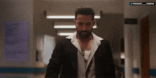 a man in a suit is walking down a hallway with the words pranay varma on the bottom right