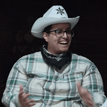 a woman wearing a cowboy hat and glasses is clapping