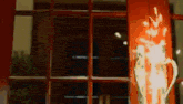 a vase is sitting in front of a window with a red wall behind it .