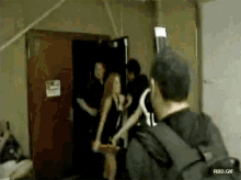 a group of people are standing in front of a door with a sign that says rbd.gif
