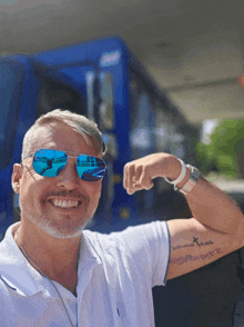 a man wearing sunglasses and a white shirt has a tattoo on his arm that says " i love you "