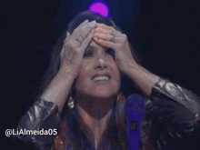 a woman with her hands on her head and a purple microphone in front of her