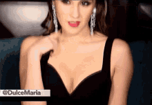 a woman is wearing a black dress and earrings and has the name dulce maria on the bottom right