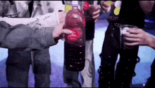 a group of people are toasting with bottles and cups of alcohol .
