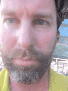 a man with a beard wearing a yellow shirt