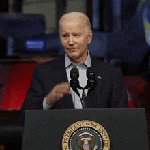 a man stands behind a podium with the seal of the president of the united states
