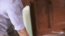 a man in a blue shirt is standing next to a wooden door .