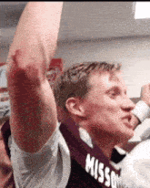 a man wearing a shirt that says missouri holds his arm in the air