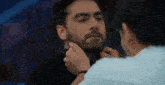 a man with a beard is being touched by another man 's neck .