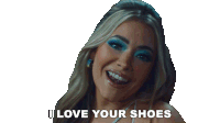 a woman with blue eye shadow is smiling and says " i love your shoes "