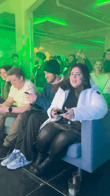 a group of people sitting in a room with green lights behind them