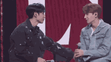 two young men are shaking hands in front of a red and white background