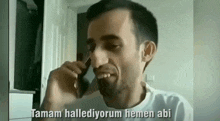 a man is talking on a cell phone in a room while smiling .