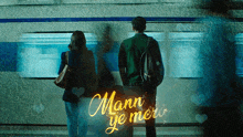 a man and woman are standing in front of a sign that says mann ye mer
