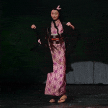 a woman in a pink and purple dress is dancing on stage