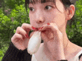a woman with red nail polish is eating a white object