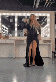 a woman in a black dress is dancing in front of a mirror .