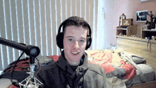 a young man wearing headphones is sitting in front of a microphone in a bedroom