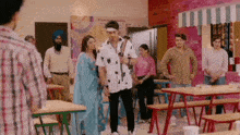 a group of people standing around tables in a restaurant .