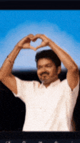 a man in a white shirt makes a heart shape with his hands