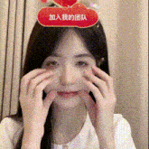 a woman is making a face with her hands while wearing a headband with chinese writing on it .