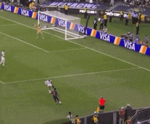a soccer field with visa advertisements on the side