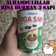 a can of indofood tiga sapi is being held in someone 's hand