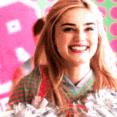 a cheerleader wearing a green and red polka dot shirt is smiling