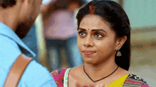 a woman with a nose ring is looking at a man in a blue shirt