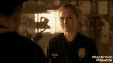 a woman in a police uniform talking to a man in a dark room .