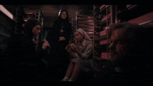 a group of people including a priest and nuns are gathered in a dark room