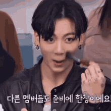 a close up of a person applying makeup with korean writing behind them