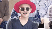 a man wearing a red hat and sunglasses is laughing .