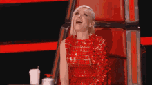 a woman in a red dress is laughing while sitting in a chair .