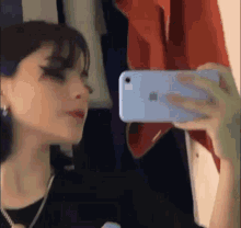 a girl is taking a picture of herself in the mirror with her phone .