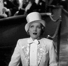 a black and white photo of a woman wearing a top hat and a tuxedo