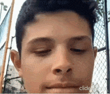 a close up of a man 's face with his eyes closed and a chain link fence in the background .