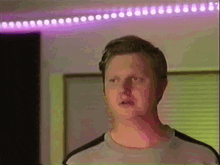 a man is standing in front of a purple and green light