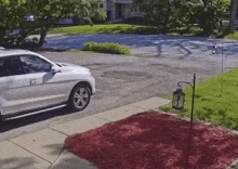 a white suv is parked in a driveway next to a lantern