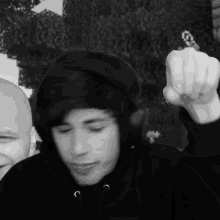 a man in a black hoodie holds up his middle finger in a black and white photo