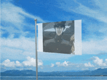 a flag with a picture of a man on it flying in the wind