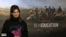 a woman standing in front of a poster for netflix 's sex education