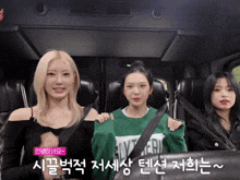 three girls are sitting in a car with one wearing a green sweatshirt that says slytherin on it