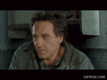 a man in a green jacket is smiling with a gifrun.com watermark on the bottom