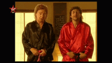 two men in black and red robes stand next to each other with a virgin logo on the bottom right