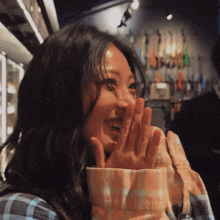 a woman covering her mouth with her hands in front of a guitar wall