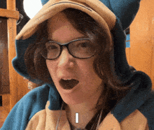 a woman wearing glasses and a pokemon costume has the letter i on her face