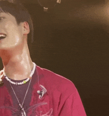 a man wearing a pink shirt and a pearl necklace is smiling